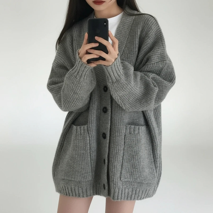 Person wearing a gray cardigan taking a mirror selfie.
