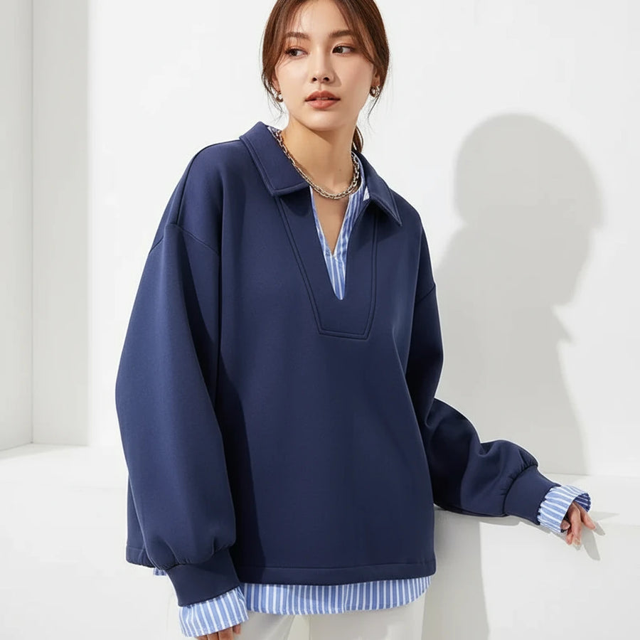 Blue sweatshirt with a striped shirt underneath on a hanger, with 'NEW Arrivals' sign in the background.