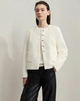 Woman wearing a white textured jacket with black pants on a plain background, featuring the brand 'Amii'.