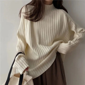 Person wearing a white ribbed sweater with a neutral background
