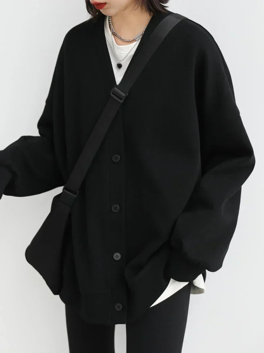 Person wearing a black cardigan over a white shirt on a white background