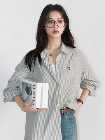 Woman wearing a striped shirt and jeans, holding a book against a white background