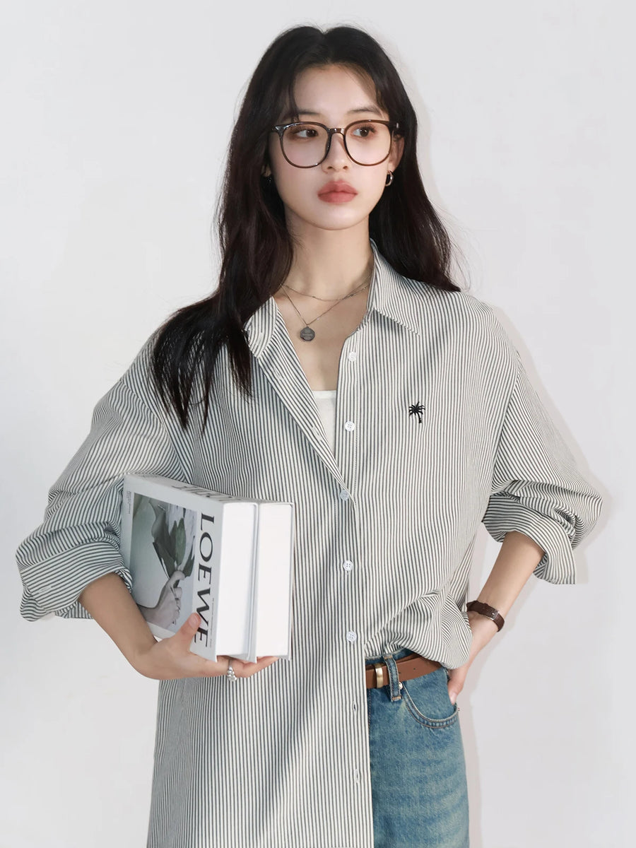 Woman wearing a striped shirt and jeans, holding a book against a white background
