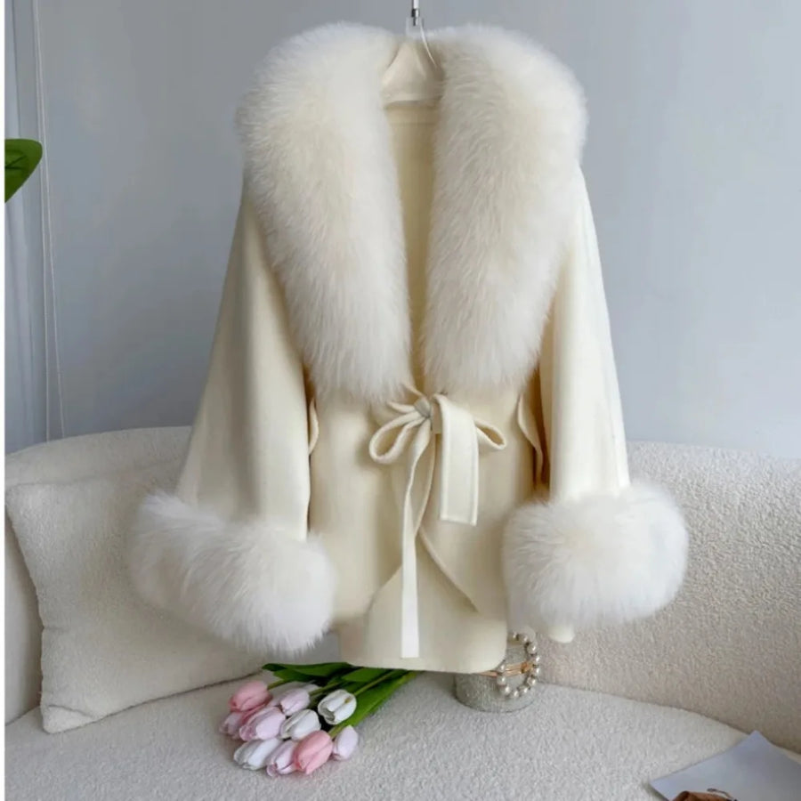 White fur coat with pom-pom details on a white surface