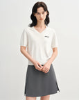 Woman wearing a white polo shirt and gray skirt on a white background