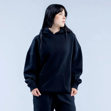 Person wearing a black hoodie against a light gray background