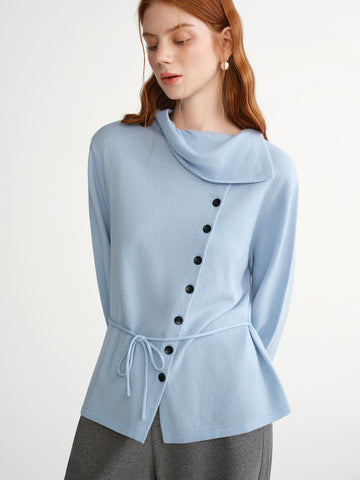 Woman wearing a light blue poncho with black buttons on a white background