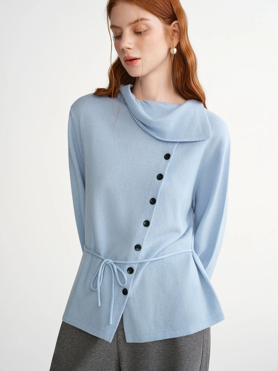 Woman wearing a light blue poncho with black buttons on a white background