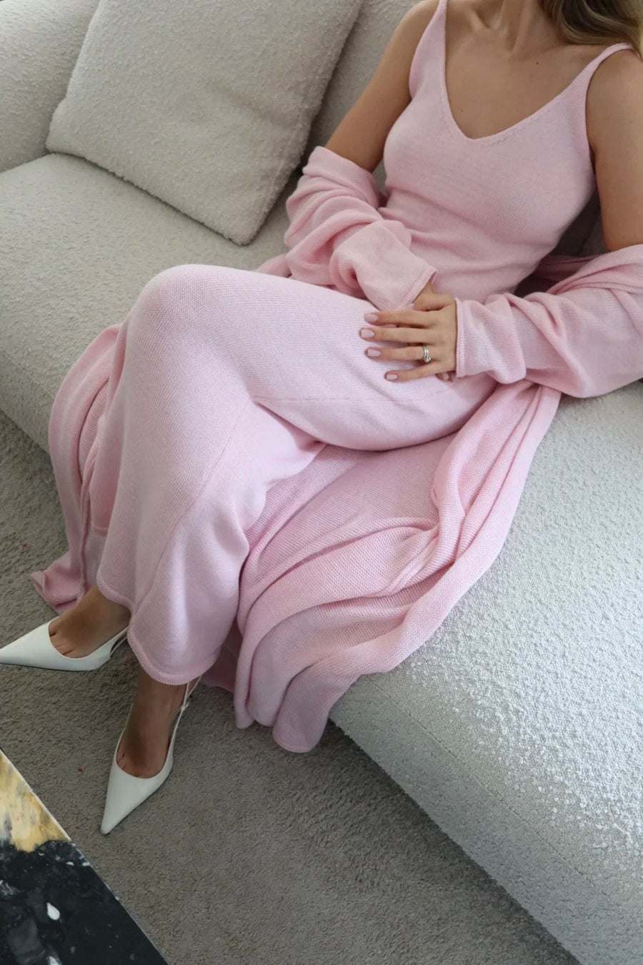 Person wearing a pink dress sitting on a couch.