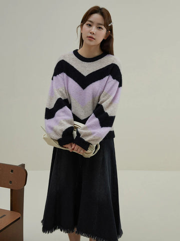 Woman wearing a colorful sweater and black skirt in a minimalistic setting