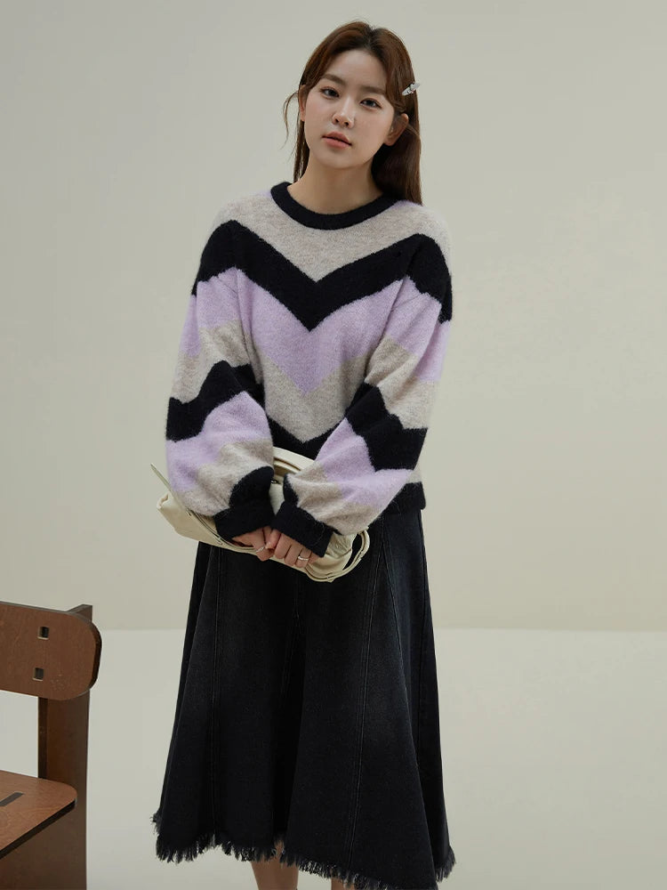 Woman wearing a colorful sweater and black skirt in a minimalistic setting