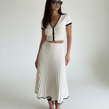 Woman in a white outfit with black trim standing on a staircase.