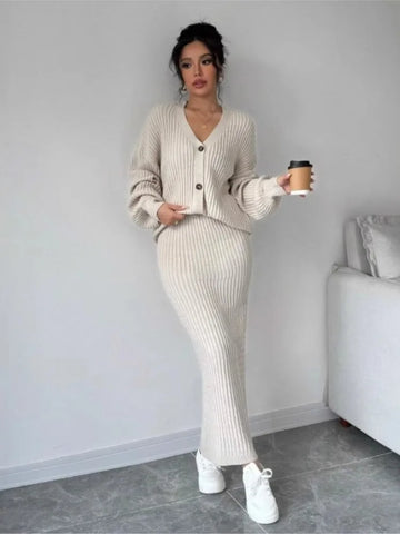 Woman in a beige ribbed sweater and pants holding a coffee cup indoors.