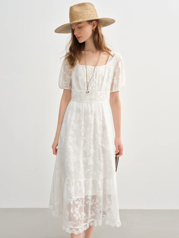 Woman wearing a white lace dress and straw hat on a plain background