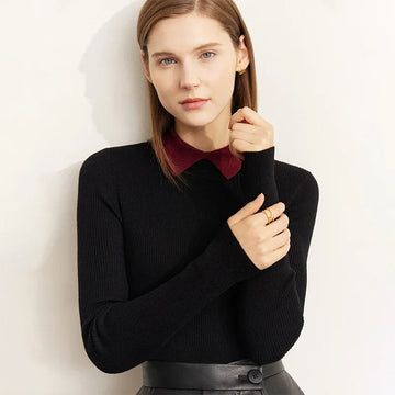Woman wearing a black sweater over a red collared shirt against a light background
