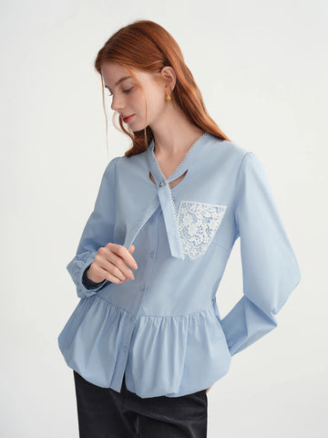 Woman wearing a light blue blouse with lace detailing on a white background