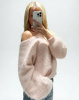 Person wearing a fluffy pink sweater taking a mirror selfie.