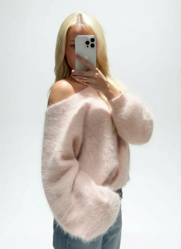 Person wearing a fluffy pink sweater taking a mirror selfie.