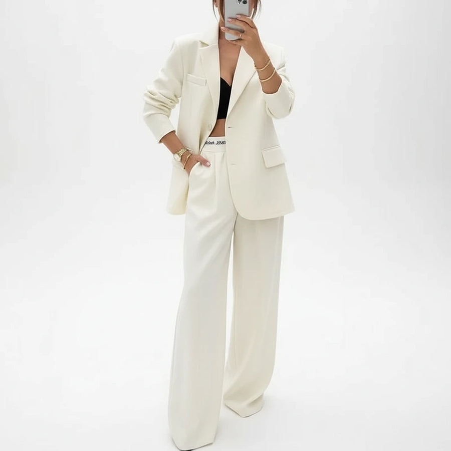 Person wearing a beige suit taking a mirror selfie.