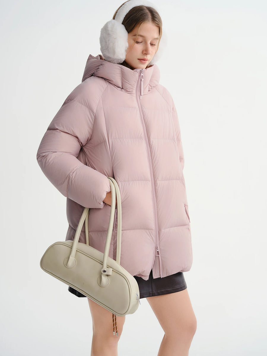 Person wearing a pink puffer jacket and white ear muffs on a white background